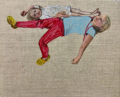 Two children playfully lying on a textured surface, one resting on the other's back.