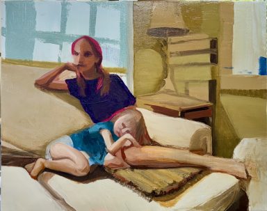 A woman sitting on a couch with a child resting beside her, in a cozy interior setting.