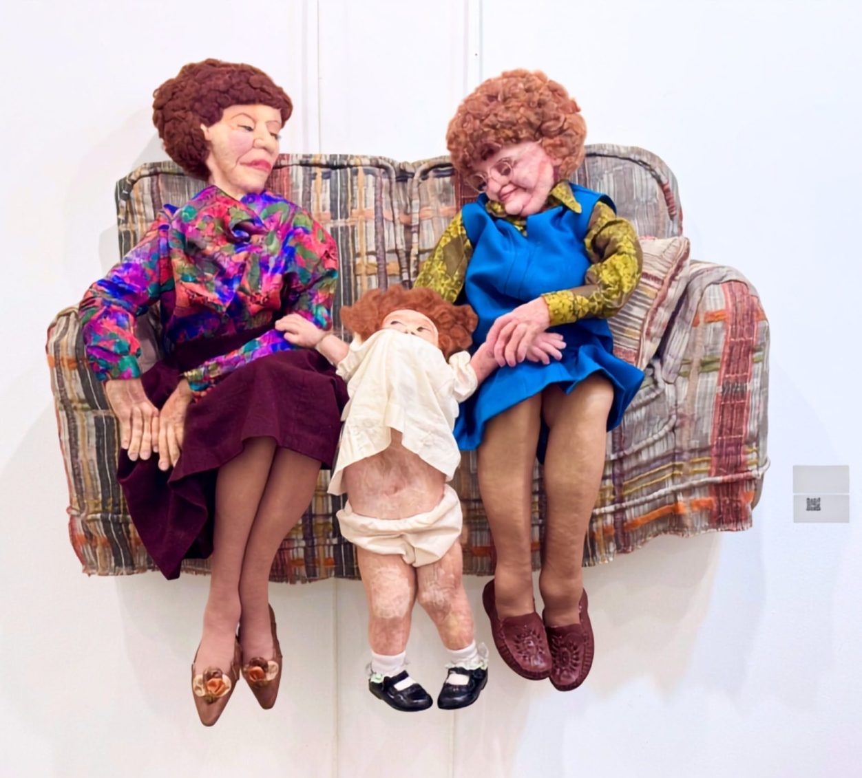Inheritance, Soft Sculpture by Emily Flint Contemporary Soft Sculpture of two elderly women with a toddler wedged between them on a loveseat.